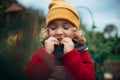 Little girl in autumn clothes eating harvested organic peas in eco garden, sustainable lifestyle. Royalty Free Stock Photo