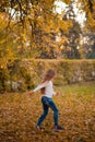 Little girl in autumn orange leaves. happy little child, baby girl laughing and playing in the autumn on the nature walk outdoors. Royalty Free Stock Photo