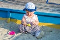 Little girl baby in a cap plays with toys in a sandbox with sand on the playground Royalty Free Stock Photo