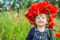 Little girl baby playing happy on the poppy field with a wreath, a bouquet of color A red poppies and white daisies, wearing a den Royalty Free Stock Photo
