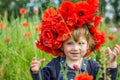 Little girl baby playing happy on the poppy field with a wreath, a bouquet of color A red poppies and white daisies, wearing a den Royalty Free Stock Photo