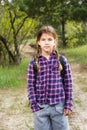 Little girl with backpack traveling in the forest