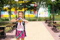 Little girl with a backpack and in a school uniform in the school yard plays pop it toy. Back to school, September 1. The pupil