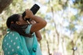 Little girl with backpack taking photos from dslr camera on a sunny day Royalty Free Stock Photo