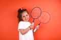 Little girl with badminton rackets. 7 years old child in a white t-shirt in the studio. The concept of children`s sports