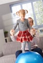 Little girl balancing on fit ball father helping