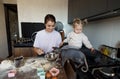 a little girl and a bald sphinx cat watch attentively as a caring mother cooks food in the kitchen Royalty Free Stock Photo