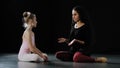 Little girl ballerina dancer beginner acrobat child in leotard sits on floor in dance class with adult woman teacher