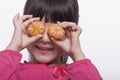 Little girl with bangs holding mandarins in front of her eyes, head and shoulders studio shot