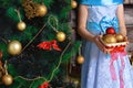 Little girl with a basket of Christmas decorations. It stands near Christmas tree Royalty Free Stock Photo