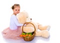 A little girl with a basket of flowers and a teddy bear is sitti Royalty Free Stock Photo