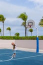 Little girl with basketball on court at tropical
