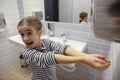 Little girl in the bathroom dries her hands with a hand dryer