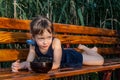 A little girl with beautiful big blue eyes lies on the bench with a bowl of fresh blachberries in front of her. Royalty Free Stock Photo