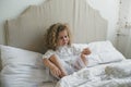 a little girl with beautiful curly hair is crying sitting in bed. Royalty Free Stock Photo