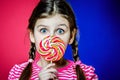 Little girl with beautiful green eyes holding a big colorful caramel candy. Royalty Free Stock Photo