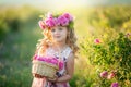 A little girl with beautiful long blond hair, dressed in a light dress and a wreath of real flowers on her head, in the Royalty Free Stock Photo