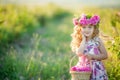 A little girl with beautiful long blond hair, dressed in a light dress and a wreath of real flowers on her head, in the Royalty Free Stock Photo