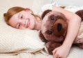 A Little girl in bed hugging the teddy bear