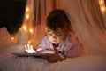 Little girl, bed and tablet at night, browsing and watching with technology for streaming or learning. Child, tech and Royalty Free Stock Photo