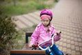 Little girl with bicycle looking upset, sitting on bench