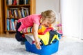 Little girl with a big basket of fresh clean laundry ready for ironing. Happy beautiful toddler and baby daughter Royalty Free Stock Photo