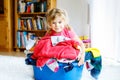 Little girl with a big basket of fresh clean laundry ready for ironing. Happy beautiful toddler and baby daughter Royalty Free Stock Photo