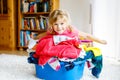 Little girl with a big basket of fresh clean laundry ready for ironing. Happy beautiful toddler and baby daughter Royalty Free Stock Photo