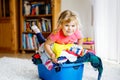 Little girl with a big basket of fresh clean laundry ready for ironing. Happy beautiful toddler and baby daughter Royalty Free Stock Photo