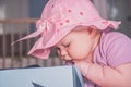 Little girl in a big purple hat looking for something in a big blue box