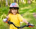 Little girl on bike in forest looking at camera and smiling Royalty Free Stock Photo