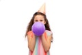 little girl in birthday party hat blowing balloon Royalty Free Stock Photo