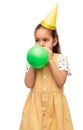 little girl in birthday party hat blowing balloon Royalty Free Stock Photo