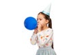 little girl in birthday party hat blowing balloon Royalty Free Stock Photo