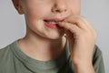 Little girl biting her nails on grey background, closeup Royalty Free Stock Photo