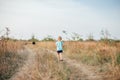 Little girl with black dog walking on the field back to camera in hot summer evening Royalty Free Stock Photo