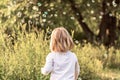 Little girl with blond hair catches soap bubbles in the park. View from the back Royalty Free Stock Photo