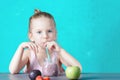 A little girl with blond hair is drinking a healthy cocktail through a straw. Vegan fruit drink. Royalty Free Stock Photo