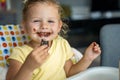 Little girl with blond hair eating homemade chocolate with dirty mouth and hands in home kitchen Royalty Free Stock Photo