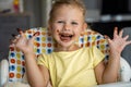 Little girl with blond hair eating homemade chocolate and showing mouth and dirty hands with stains of chocolate in home Royalty Free Stock Photo