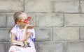 Little girl with blond hair in pigtails sits on a chair with a backpack on his back and books in his hands Royalty Free Stock Photo