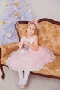 Little girl with blond hair in pink dress in new year background