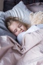 A little girl with blond hair sleeps soundly in bed. A child hugs a bear. Royalty Free Stock Photo