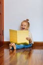 Little girl with blonde hair reading book at home Royalty Free Stock Photo