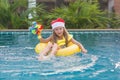 Little girl blonde in a Santa hat and swimming around in the pool, the concept of celebrating Christmas and new year in tropical Royalty Free Stock Photo