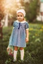 Little girl in a blooming garden or park with string shopping bag. Retro vintage fashion Royalty Free Stock Photo