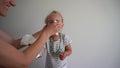 Little girl blow nose and get snotty face. Mother helping daughter clean face