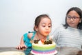 Little girl is blowing candles on her birthday cake. Celebrating at home during quarantine Royalty Free Stock Photo