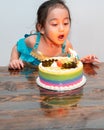 Little girl is blowing candles on her birthday cake. Celebrating at home during quarantine Royalty Free Stock Photo