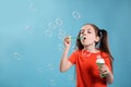 Little girl blowing soap bubbles on blue background, space for text Royalty Free Stock Photo